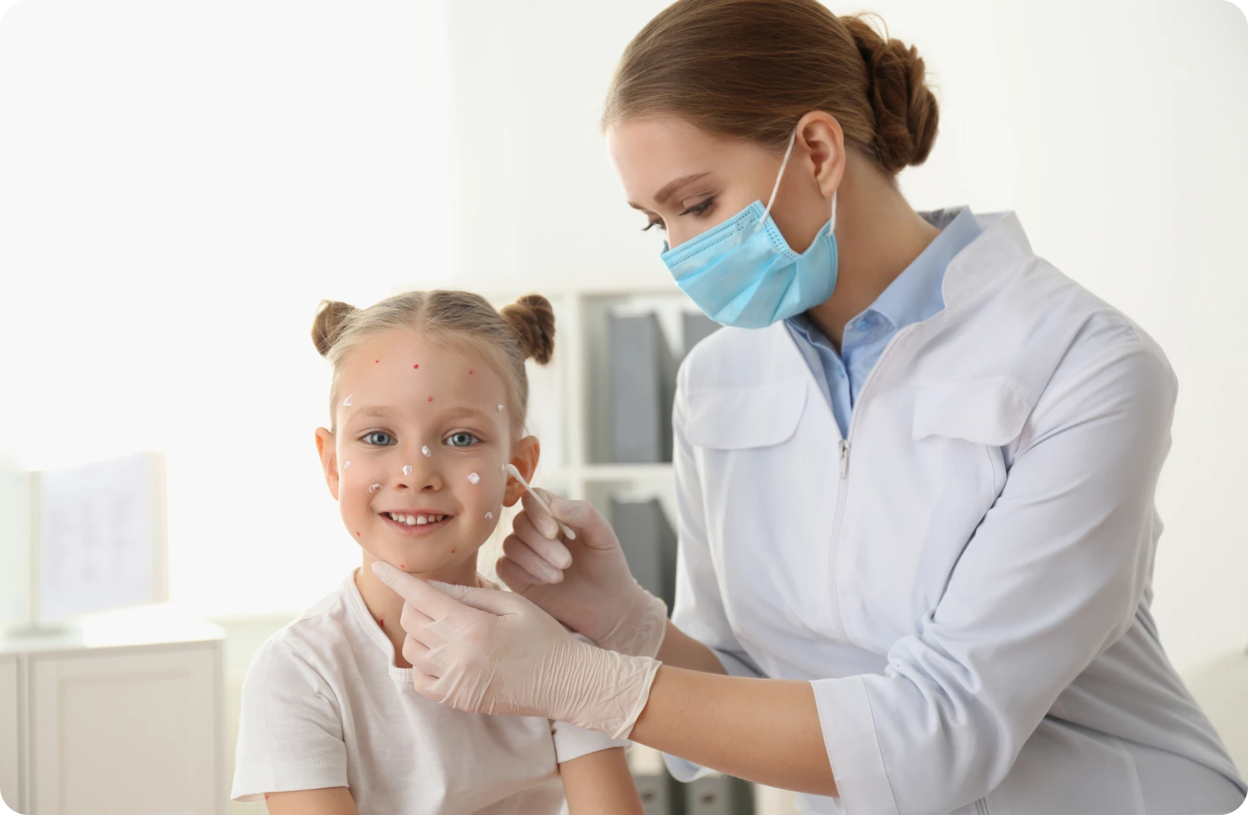 Child receiving skincare treatment from masked professional.